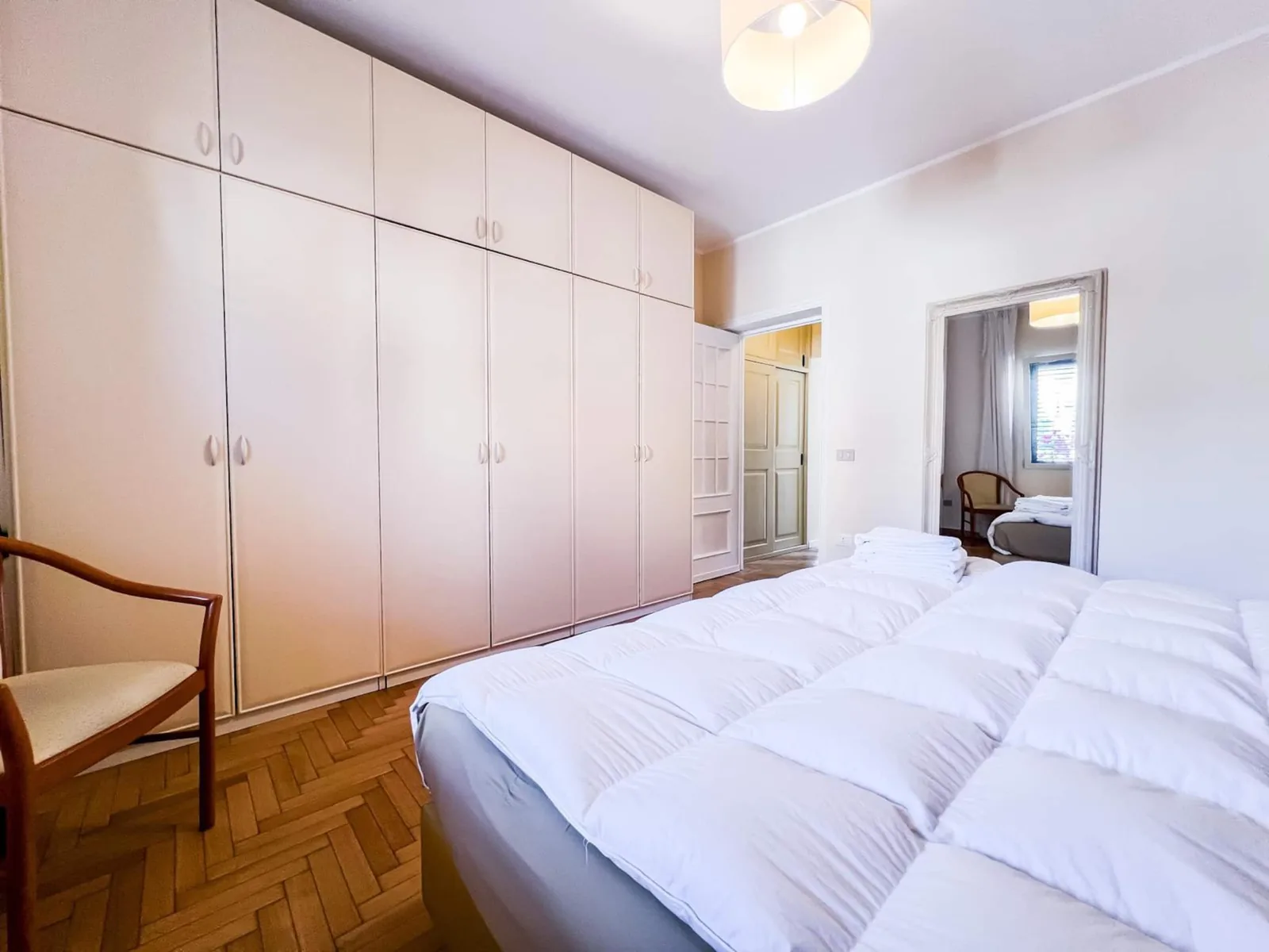 Il letto matrimoniale e la parete di armadi a muro della camera, con poltroncina