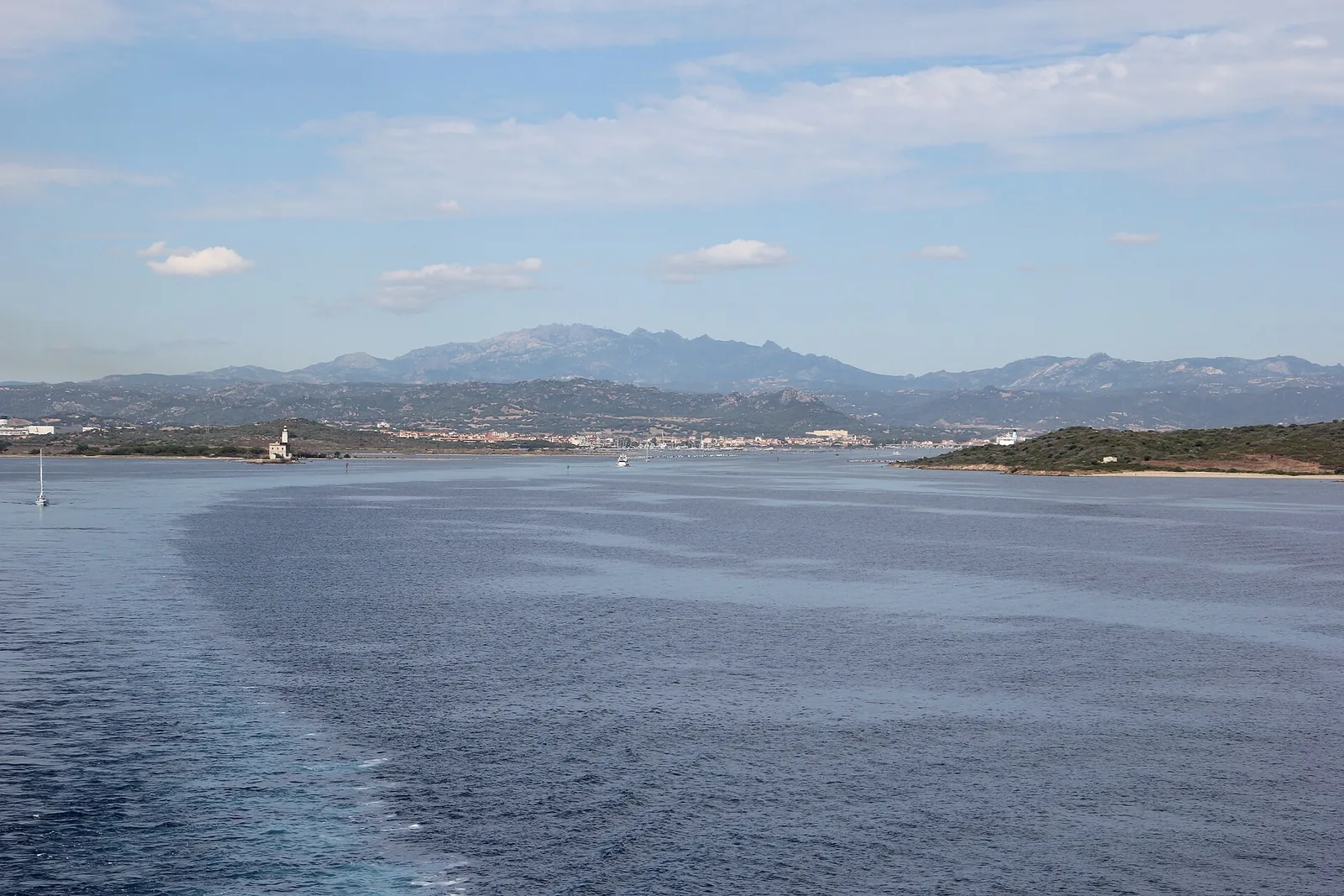 Il golfo di Olbia dal mare, il vecchio faro, la citta' sullo sfondo e i monti