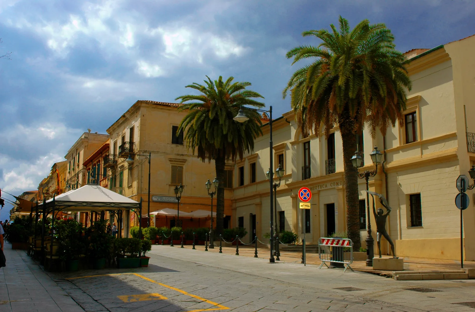 Il corso pedonale di Olbia con palme, dehors e il palazzo della biblioteca comunale